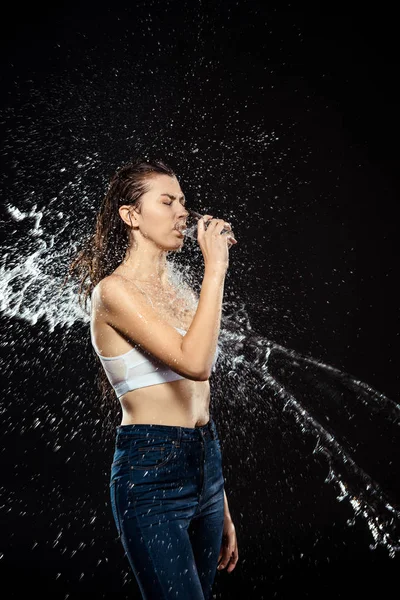 Vista laterale della donna strisciata con acqua mentre beveva acqua da vetro isolato su nero — Foto stock
