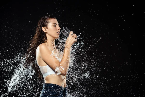 Seitenansicht der Frau mit einem Glas Wasser schwimmt mit Wasser isoliert auf schwarz — Stockfoto
