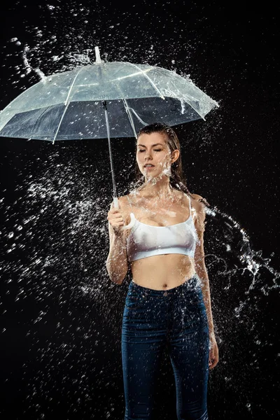 Portrait of pensive woman with umbrella swilled with water isolated on black — Stock Photo
