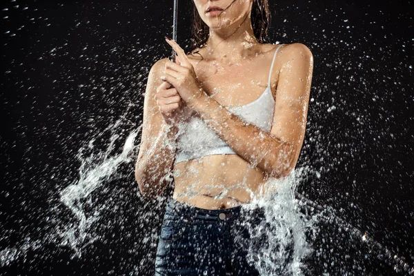 Vista parcial de mujer con paraguas hinchadas con agua aislada en negro - foto de stock