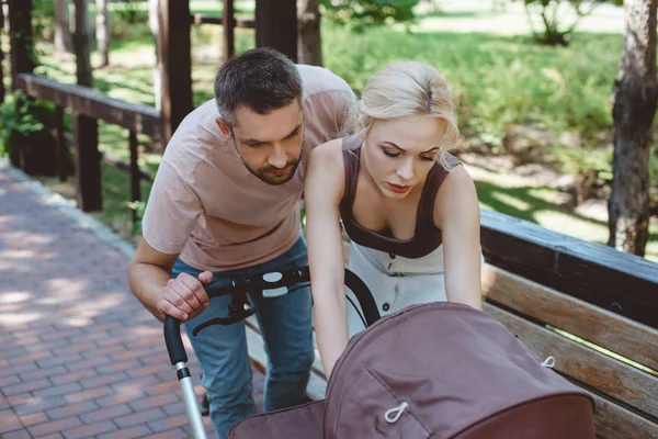 Parents looking at baby carriage in park — Stock Photo