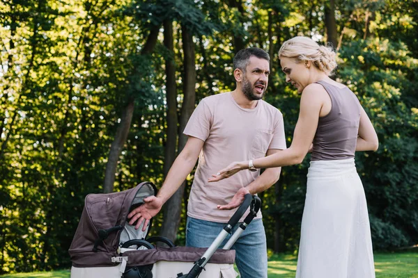 Parents hurlant et gesticulant près de la voiture de bébé dans le parc — Photo de stock