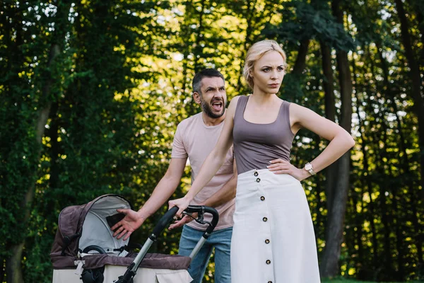 Husband screaming near baby carriage in park, wife looking away — Stock Photo