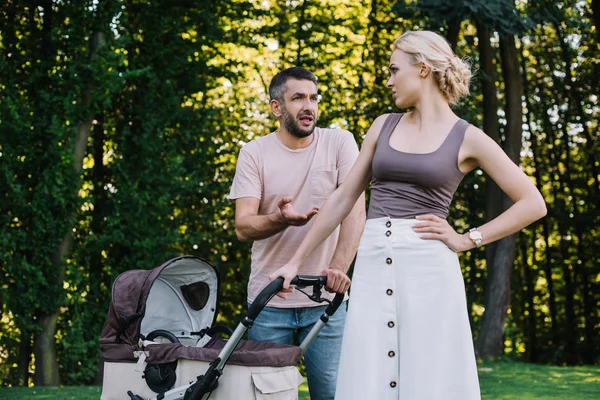 Parents quarreling near baby carriage in park — Stock Photo