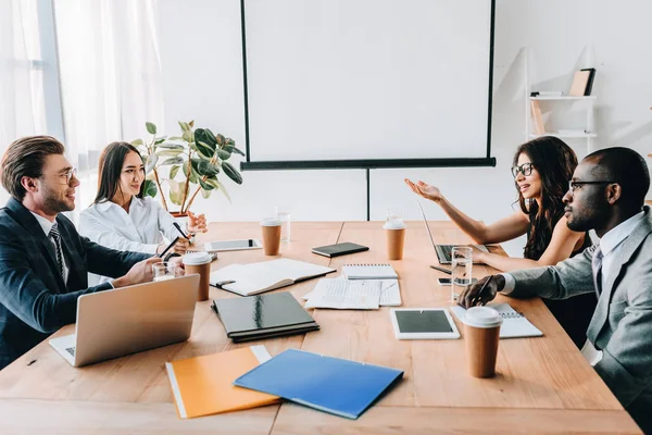 Vista lateral de las personas de negocios multiculturales que tienen reuniones de negocios en la oficina — Stock Photo