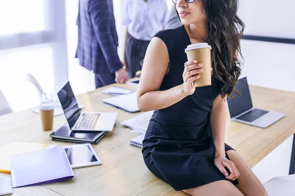 Partial view of african american businesswoman with coffee to go and colleagues behind in office — Stock Photo