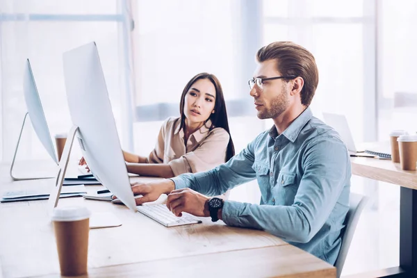 Vista lateral de colegas de negocios interraciales que trabajan juntos en proyectos en el lugar de trabajo en la oficina - foto de stock