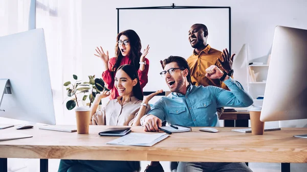 Glückliches multiethnisches Business-Team, das gemeinsam im Büro an einem Projekt arbeitet — Stockfoto