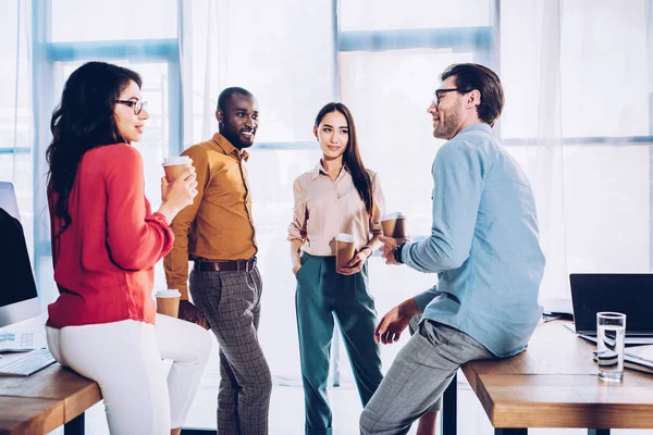 Interracial business colleagues having conversation during coffee break in office — Stock Photo