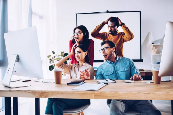 Impactado equipo de negocios multirracial trabajando en el proyecto juntos en la oficina - foto de stock