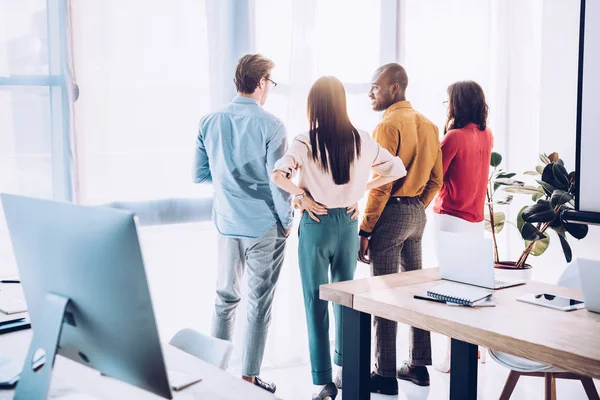 Rückansicht multiethnischer Geschäftskollegen, die im Büro aus dem Fenster schauen — Stockfoto