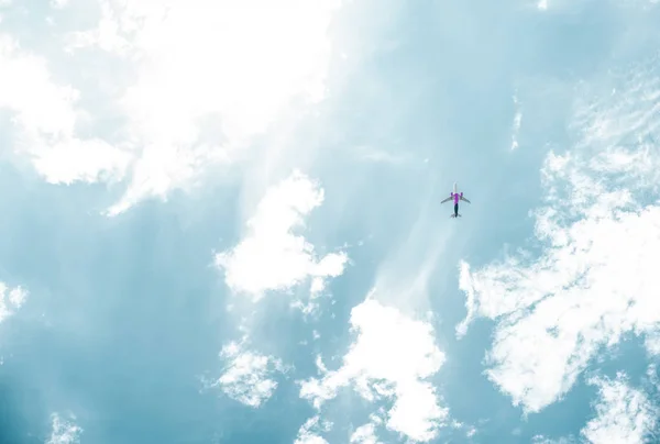 Bottom view of airplane flying in blue sky with white clouds — Stock Photo