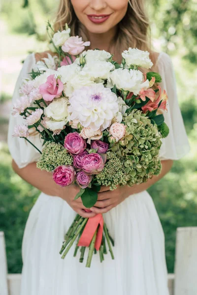 Plan recadré de mariée blonde souriante tenant beau bouquet de mariage — Photo de stock