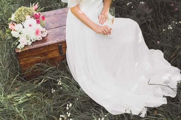 Высокий угол обзора невесты держа бокал шампанского и сидя на винтажной груди — стоковое фото
