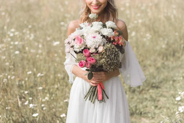 Close-up view of beautiful smiling bride holding bouquet of flowers — Stock Photo