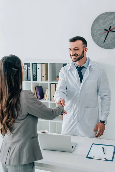 Medico paziente e sorridente che stringe la mano in clinica — Foto stock