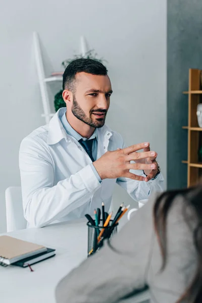 Schöner Arzt im weißen Kittel im Gespräch mit Patient in Klinik — Stockfoto