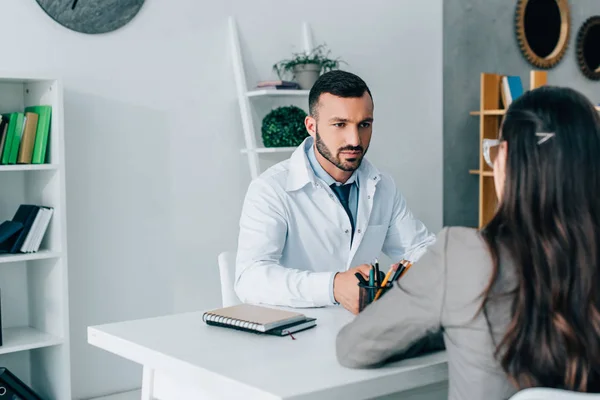 Handsome doctor talking to patient in clinic — Stock Photo