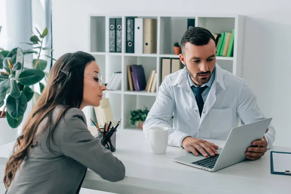 Patient and general practitioner looking at laptop in clinic — Stock Photo