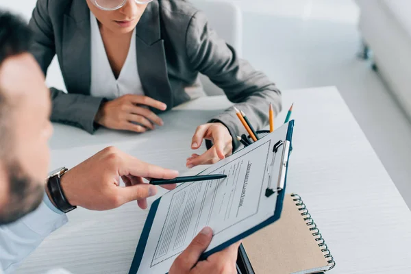 Cropped image of doctor pointing on insurance claim form to patient in clinic — Stock Photo