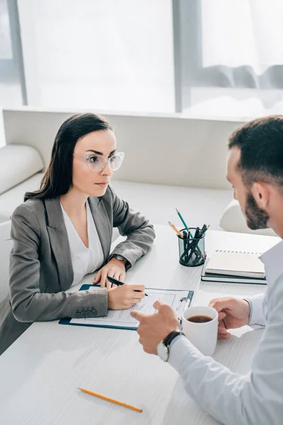 Patient unterschreibt Versicherungsantragsformular in Klinik, Arzt trinkt Tee — Stockfoto