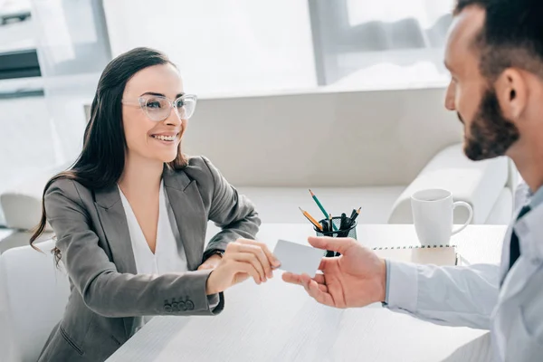 Paciente sonriente dando tarjeta de identificación al médico en la clínica - foto de stock