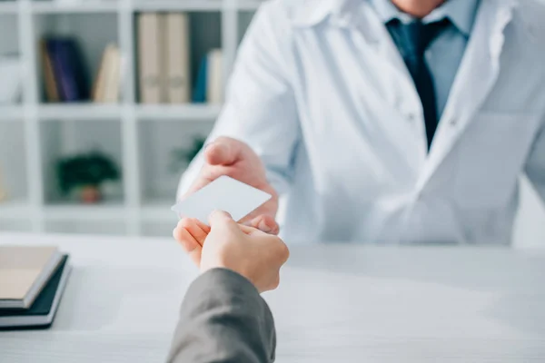 Cropped image of patient giving id card to general practitioner in clinic — Stock Photo