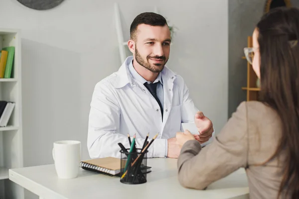 Patient gibt Ausweis an gut gelaunten Arzt in Klinik — Stockfoto