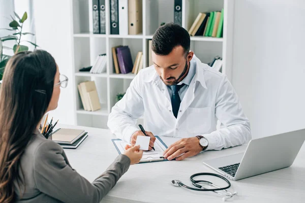 Patient giving id card to general practitioner to fill insurance claim form in clinic — Stock Photo