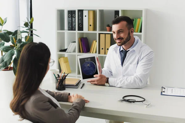 Médecin généraliste souriant montrant patient ipad en clinique — Photo de stock