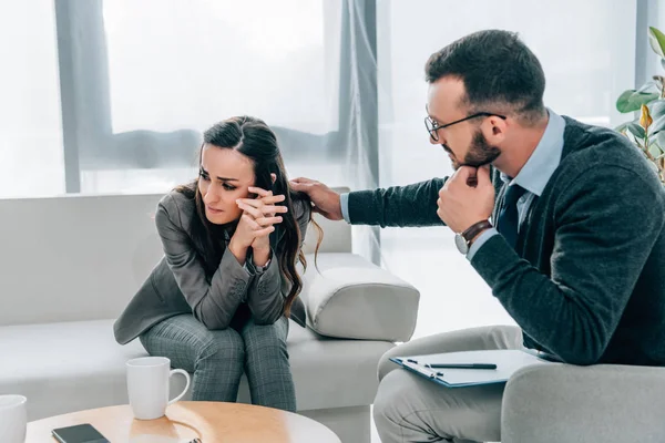 Psychologe berührt weinende Patientin in Arztpraxis an der Schulter — Stockfoto