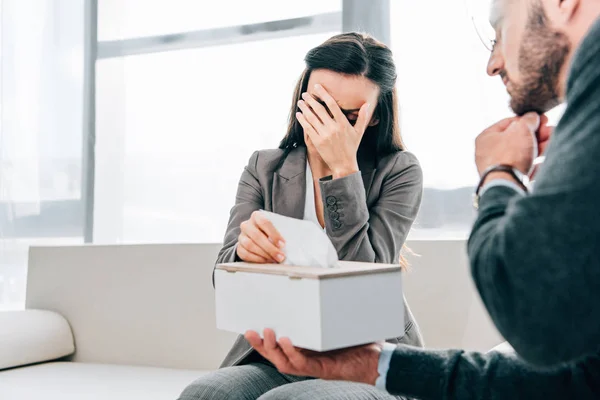 Psychologist giving napkins to crying patient in doctors office — Stock Photo