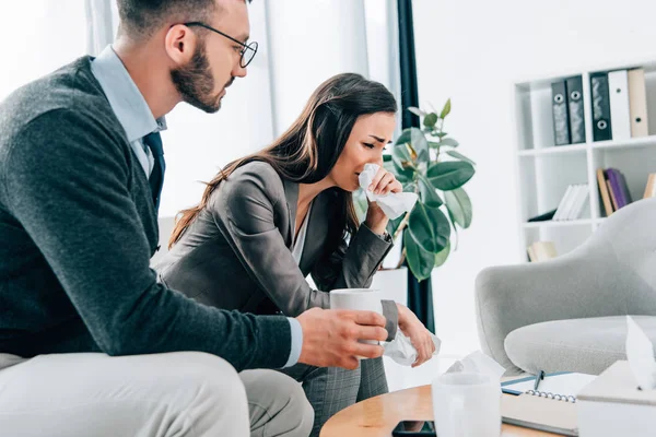 Psychologist giving cup of tea to crying female patient in doctors office — Stock Photo