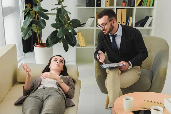 Paciente acostado en el sofá y hablando con el psiquiatra en el consultorio — Stock Photo