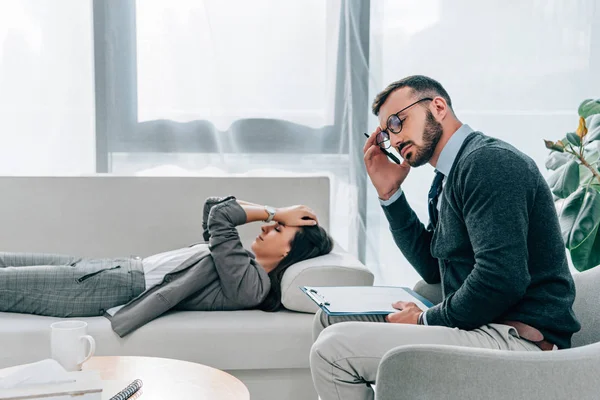 Paciente deprimido acostado en el sofá, psicólogo cansado sentado en el sillón - foto de stock