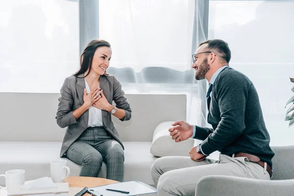 Zufriedene Patientin berührt Brust und schaut Psychologin im Büro an — Stockfoto