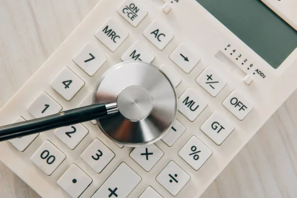 Stethoskop von oben auf weißem Taschenrechner, Krankenversicherungskonzept — Stockfoto