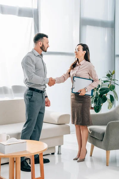 Psychologist and patient shaking hands in office — Stock Photo