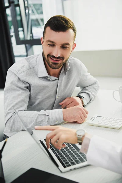 Doctor showing something on laptop to male client in office — Stock Photo