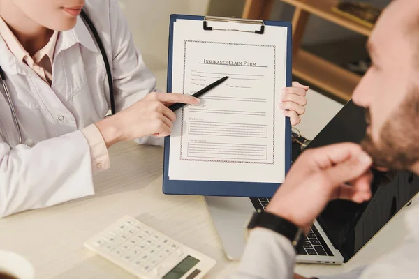 Visão cortada do médico mostrando formulário de pedido de seguro ao cliente — Fotografia de Stock