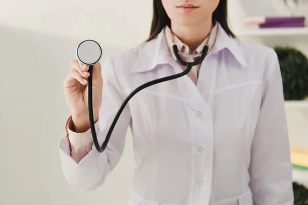 Vue recadrée du médecin femme en manteau blanc tenant stéthoscope — Photo de stock