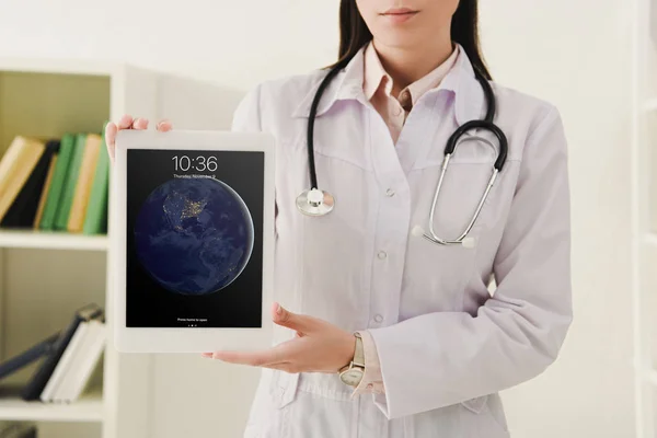 Vue recadrée du médecin avec stéthoscope montrant ipad — Photo de stock