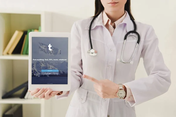 Cropped view of doctor with pointing at digital tablet with tumblr app — Stock Photo