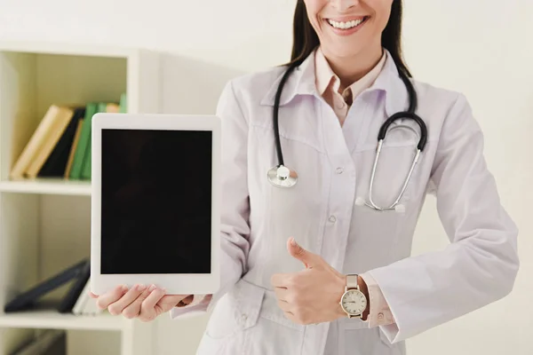 Vista cortada do médico mostrando polegar para cima e apresentando tablet digital com tela em branco — Stock Photo