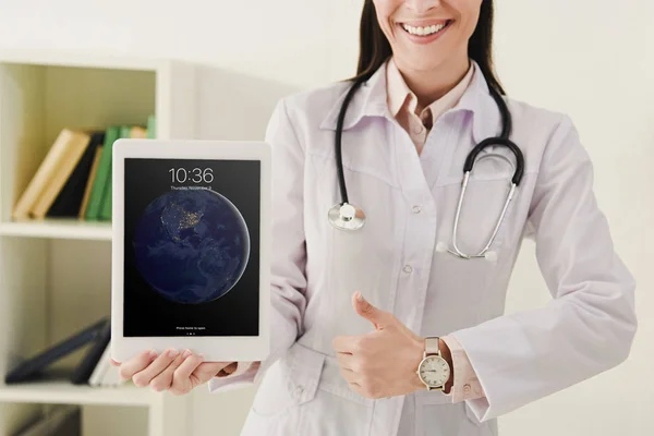 Vista cortada do médico mostrando polegar para cima e apresentando ipad — Fotografia de Stock