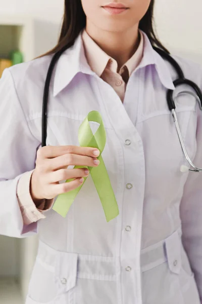 Vista cortada do médico em casaco branco segurando fita verde - dia de saúde mental — Fotografia de Stock