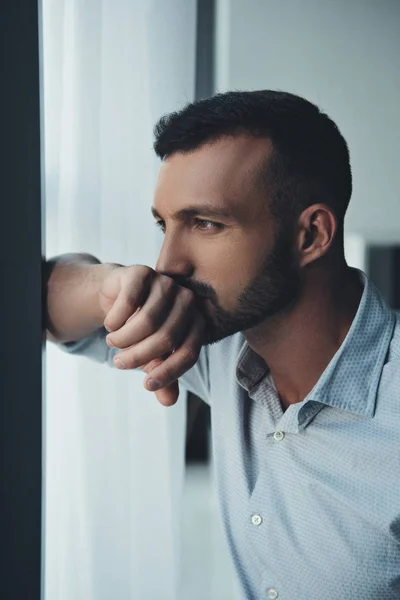 Nachdenklicher Mann steht zu Hause am Fenster — Stockfoto