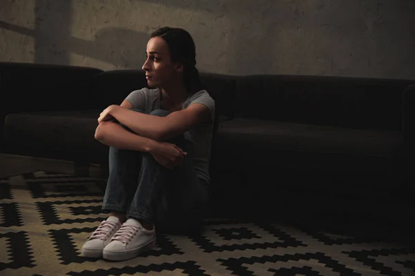 Beautiful upset woman sitting on floor at home — Stock Photo