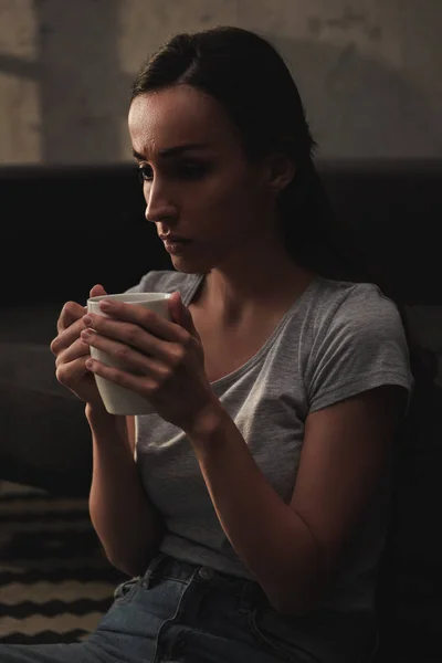 Грустная эмоциональная женщина держит чашку кофе — стоковое фото