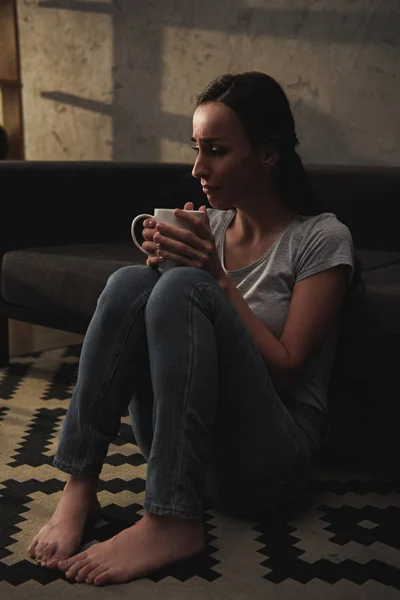 Расстроенная женщина плачет и держит чашку кофе — стоковое фото